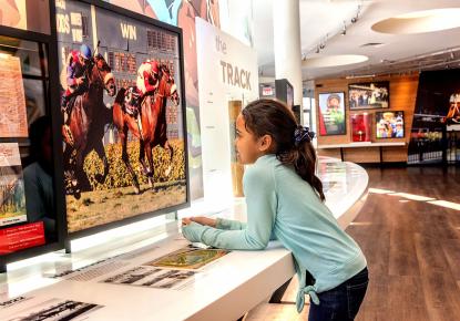A kid using an interactive exhibit at the national thoroughbred racing musem and hall of fame